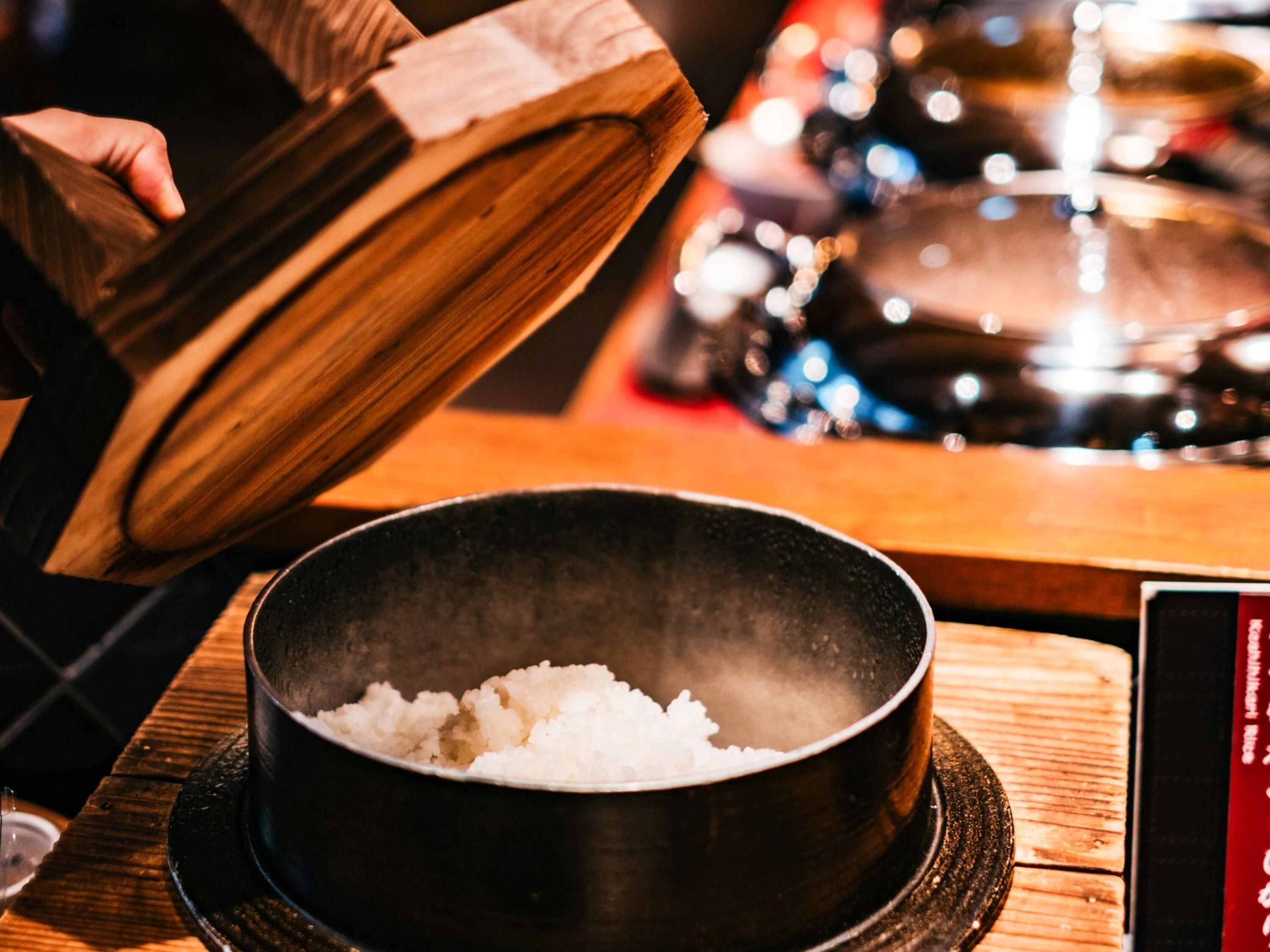 A bowl of white rice on a wooden table.
