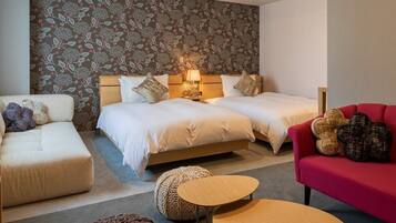 A hotel room with two beds, a red sofa, a beige sofa, and a small wooden table.