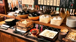 Buffet com diversos alimentos, incluindo tigelas de arroz, pratos de peixe e cestos de legumes.