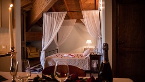 Une chambre confortable avec un lit, une table de chevet sur laquelle se trouve une bouteille, et une table avec des verres à vin et des roses.