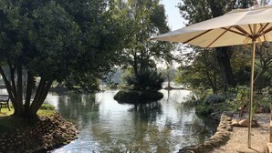 Un cadre extérieur paisible avec un étang, des marches en pierre et un parasol.