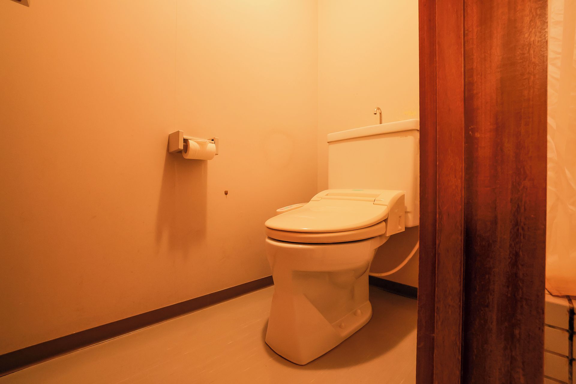 A toilet in a bathroom with a toilet paper holder on the wall.