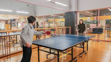 Une table de ping-pong dans une pièce dont le sol est en bois et qui est séparée par des cloisons en verre.