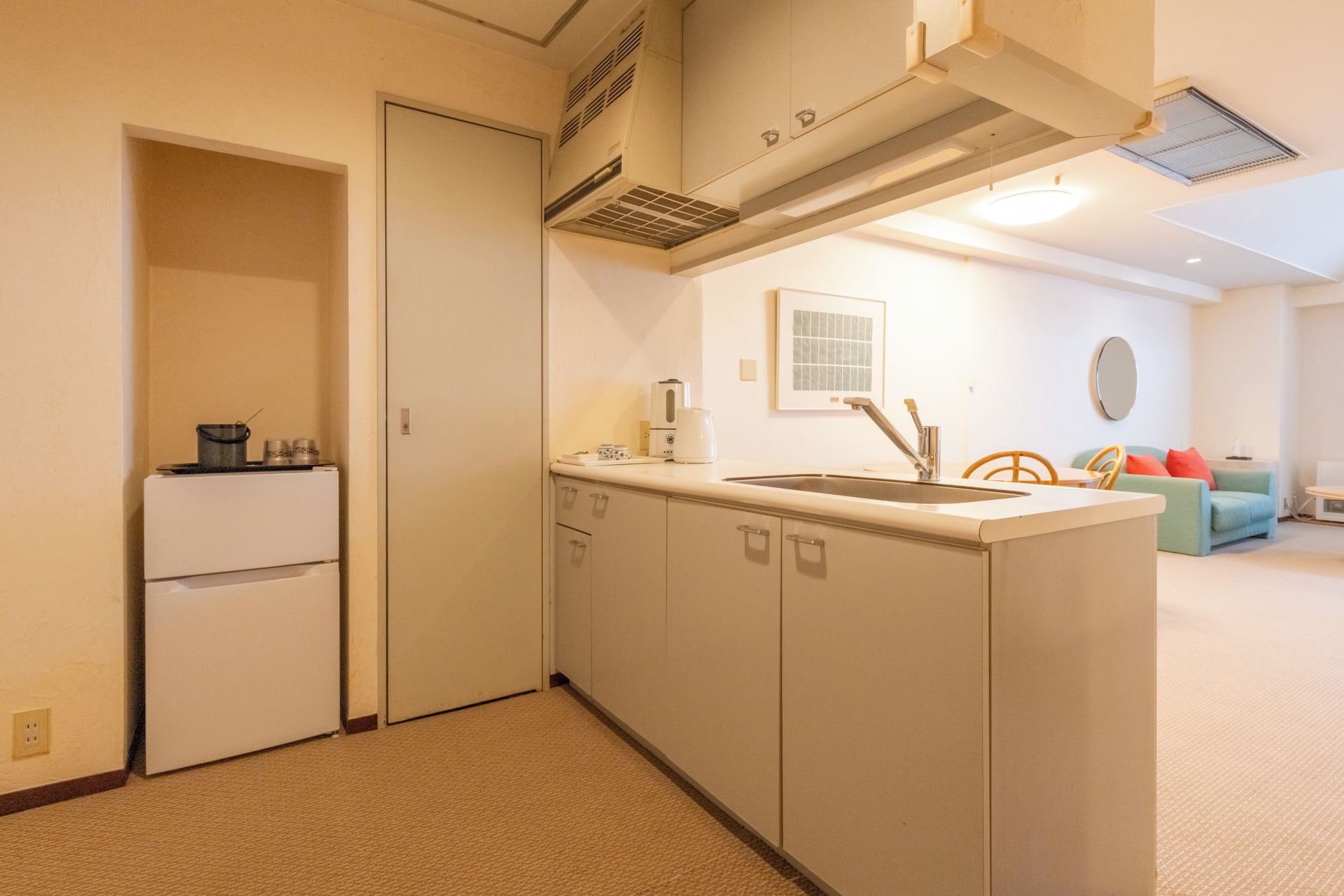 A compact kitchen with a built-in oven, a sink, and a coffee maker.