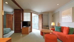 A modern living room with a red sofa, wooden furniture, a TV, and a view through a glass door. - Fuji Premium Resort (Fujikawaguchiko)