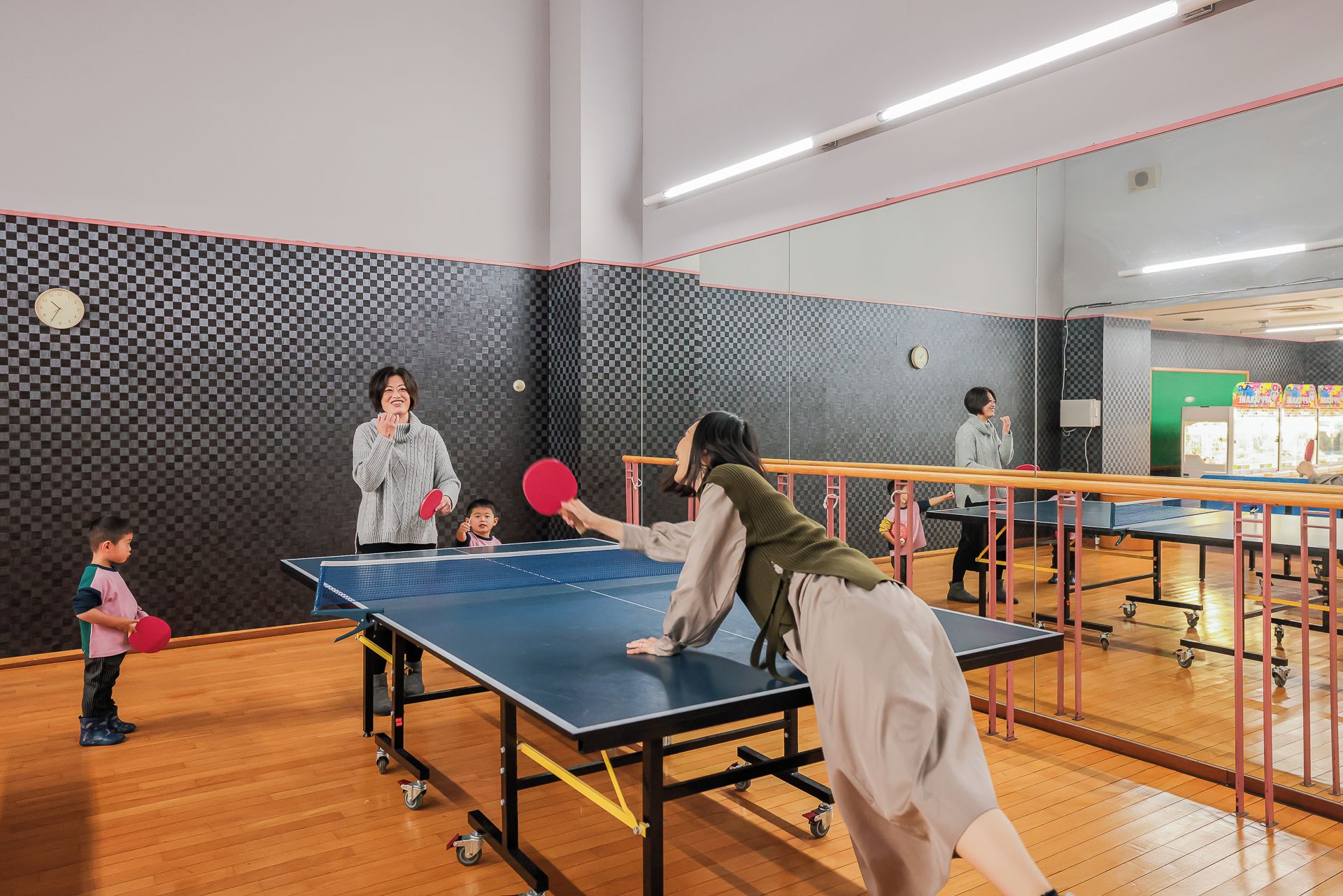 A ping pong table in a room with a checkered wall pattern and a clock.