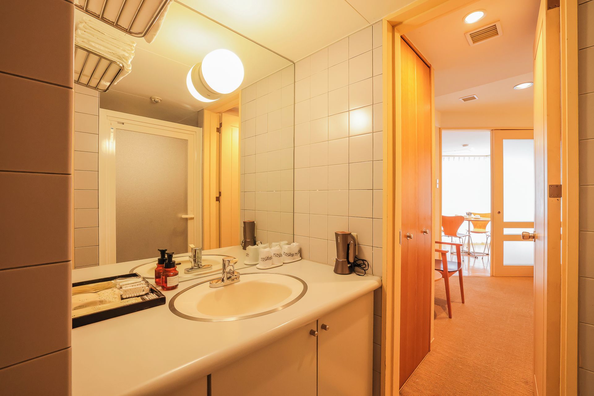 A hotel bathroom with a sink, mirror, and toiletries.