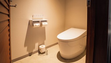 Un baño pequeño con inodoro, dispensador de toallas de papel y rollo de papel higiénico.