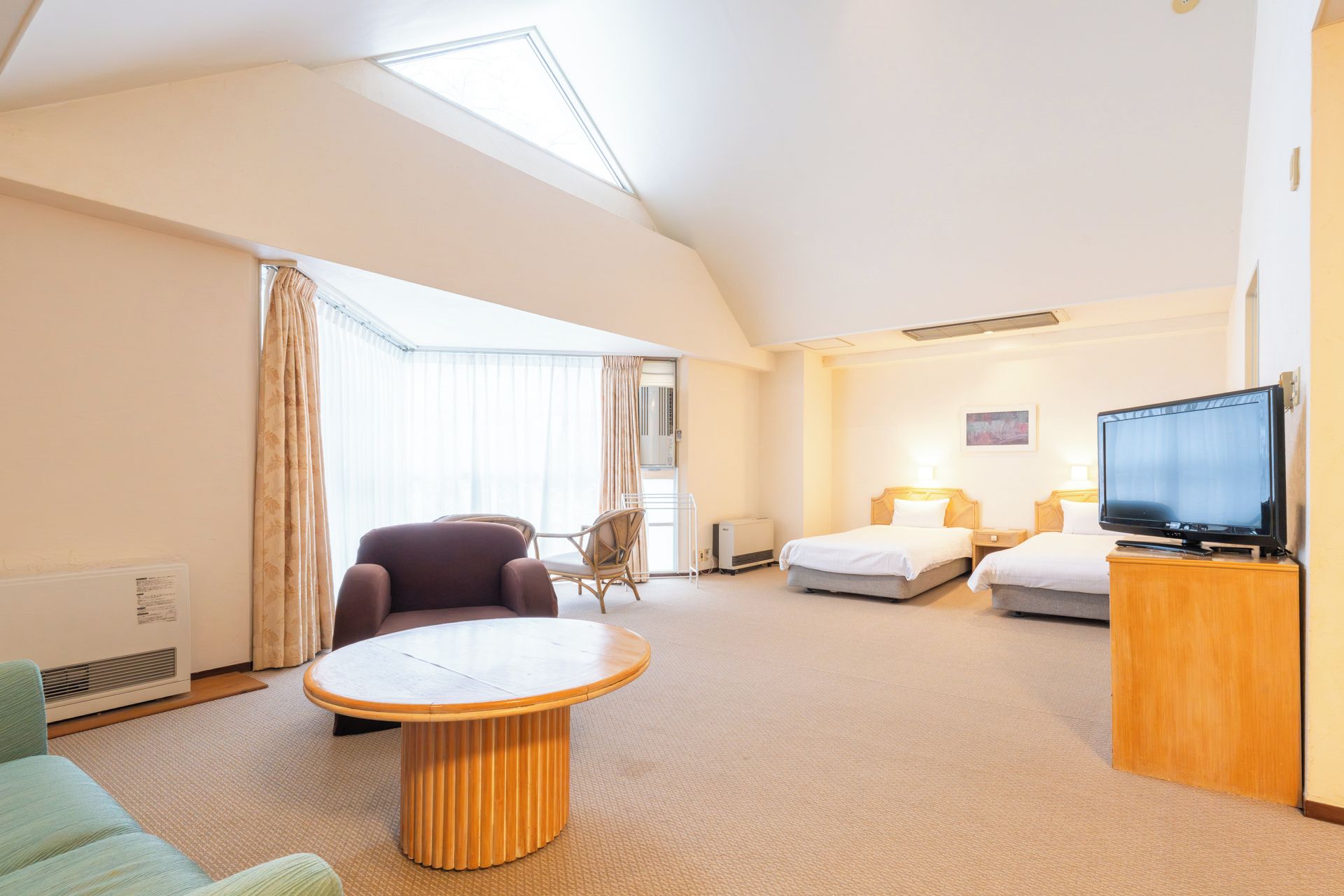 A hotel room with a large bed, a TV, a round table, and a chair.