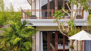 A modern two-story building with a balcony, large windows, and lush greenery. - Lebak Bali Residence (Canggu)