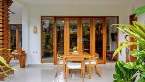 A wooden dining table with chairs, a large vase, and a wooden column. - Lebak Bali Residence (Canggu)