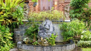 A circular stone pond with statues and plants. - Lebak Bali Residence (Canggu)