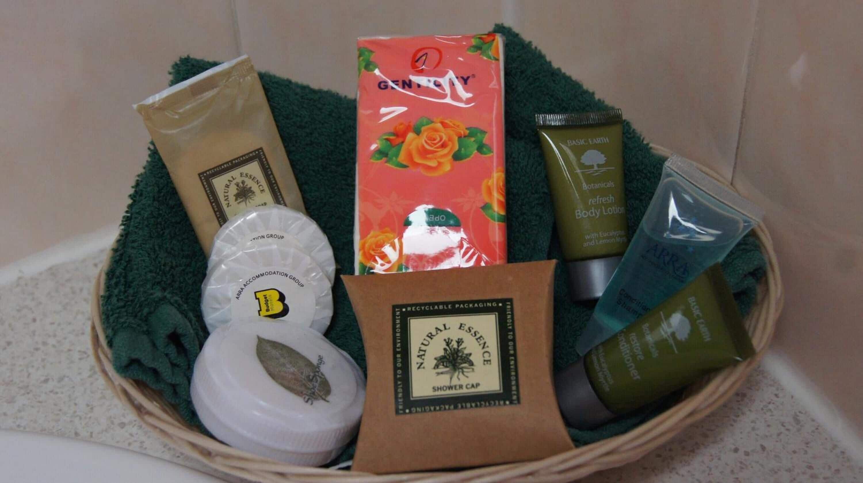 Una cesta con artículos de aseo como gorro de ducha, loción corporal y champú.