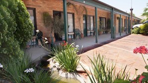 A row of rooms with a brick facade, green awnings, and outdoor seating areas. - Ningana Motel (Mudgee)