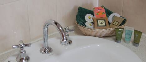 A bathroom sink with a chrome faucet, a basket of toiletries, and three bottles of skincare products.