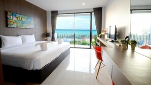 A modern hotel room with a large bed, a desk with a TV, and a balcony with a view of the sea. - The Wind (Sattahip)