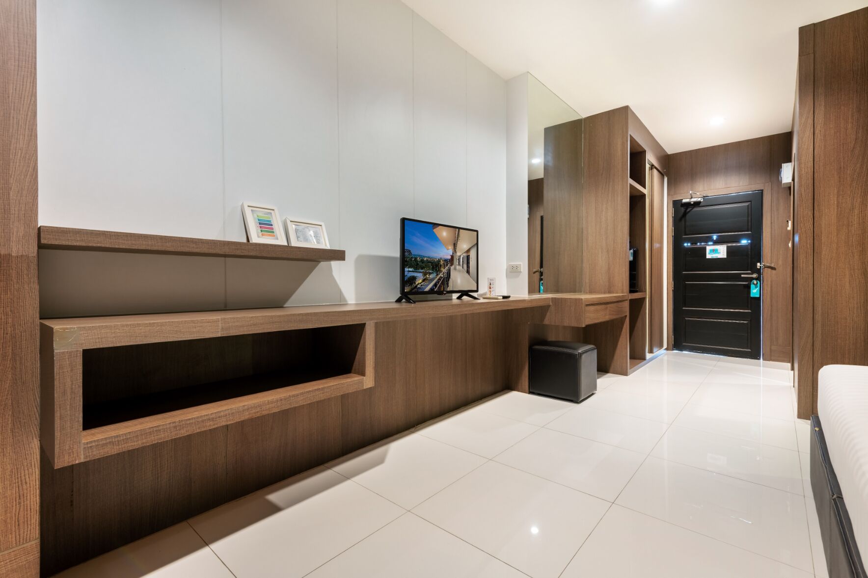 A modern hotel room with a wooden console table, a flat-screen TV, and a large mirror.