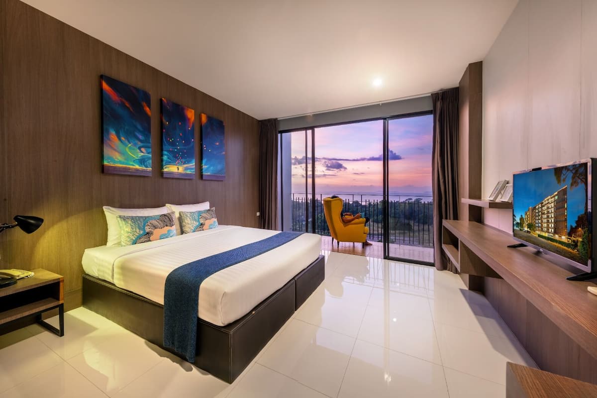 A modern hotel room with a large bed, a desk, a chair, and a TV.