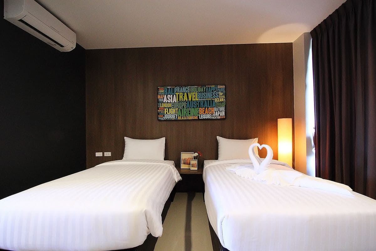 A hotel room with two beds, a wall art piece, and a nightstand with a lamp.