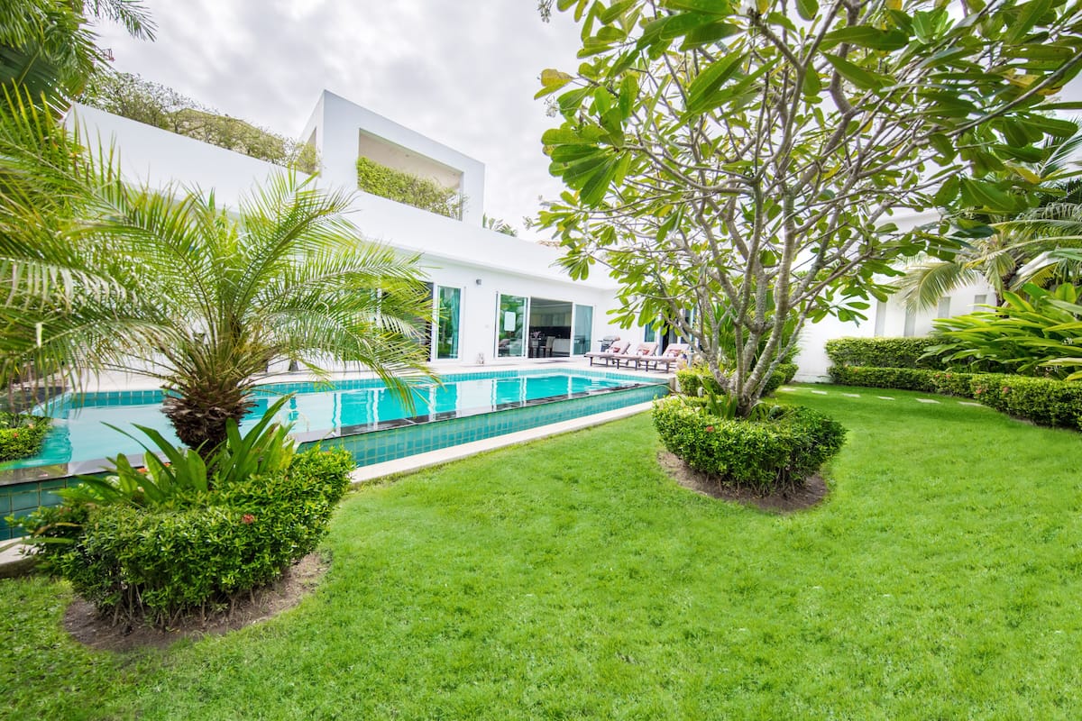 A modern building with a swimming pool, surrounded by well-maintained lawns and tropical plants.