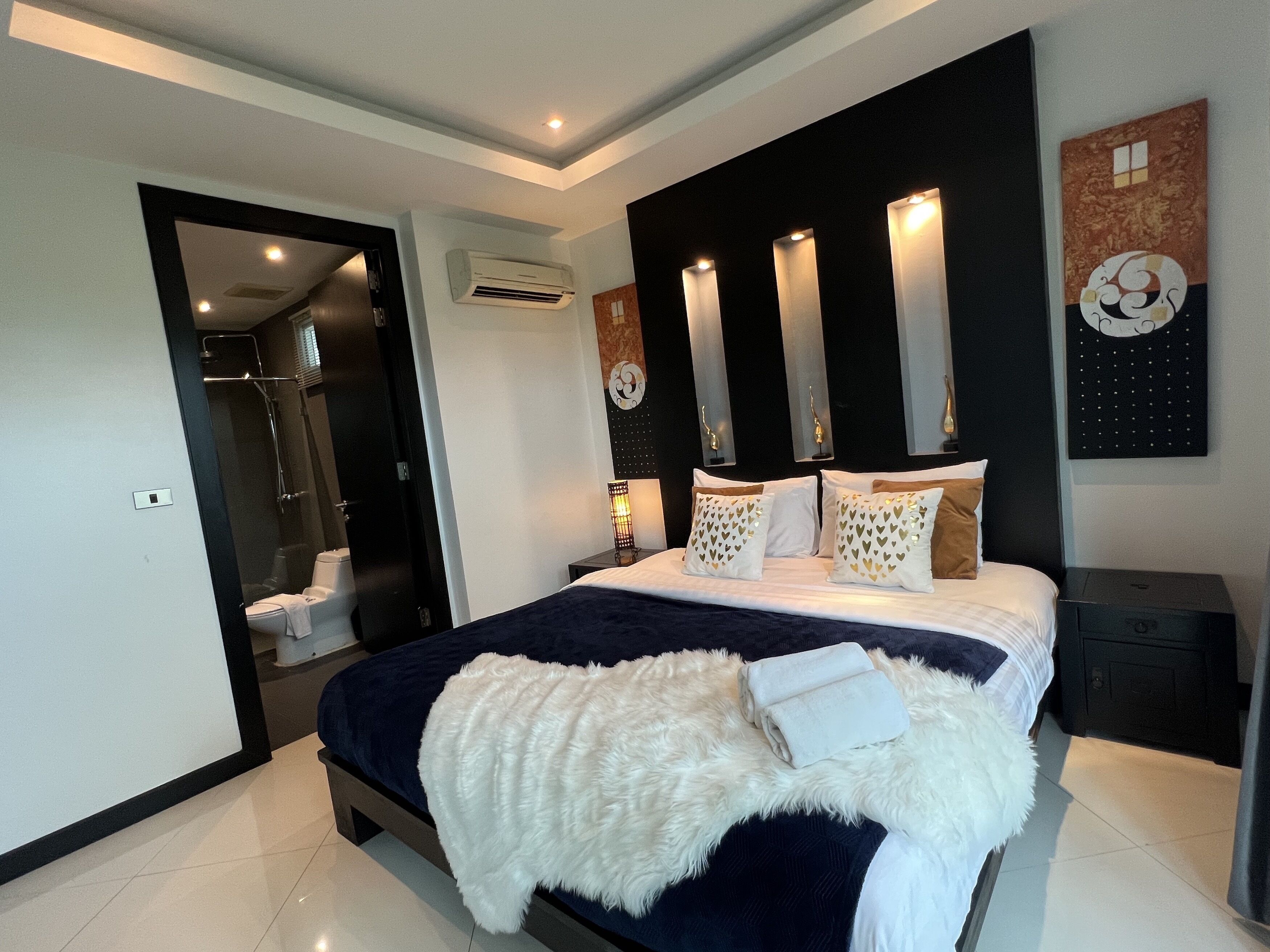 A modern bedroom with a large bed, a walk-in closet, and a bathroom with a shower.