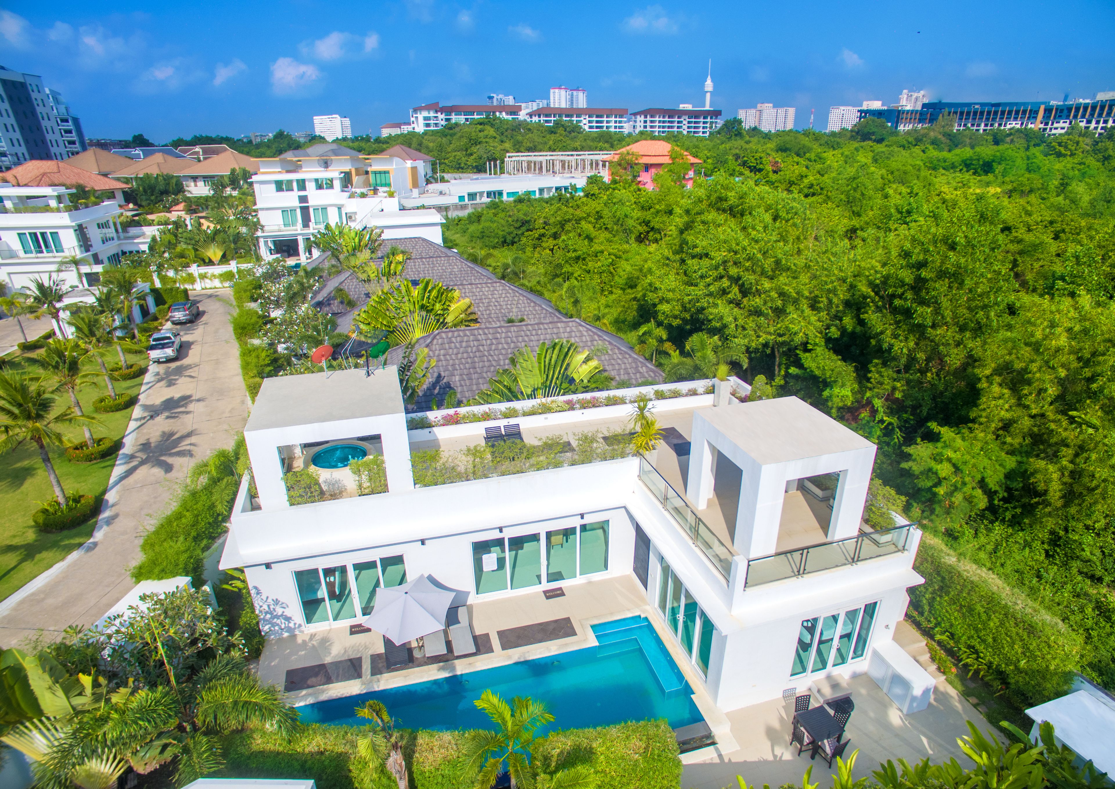 A modern house with a pool, surrounded by lush greenery and a clear blue sky.