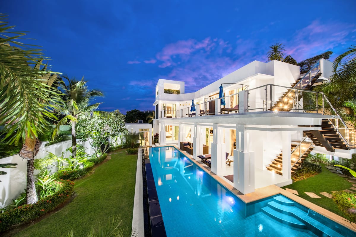 A modern house with a swimming pool, a covered outdoor area, and a staircase leading to a second floor.