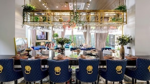 A dining area with a glass table, blue velvet chairs with gold accents, and a decorative ceiling. - Villas In Pattaya (Pattaya)