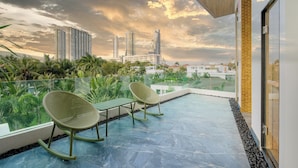 A rooftop terrace with two rocking chairs, a glass balustrade, and a view of tall buildings under a cloudy sky. - Villas In Pattaya (Pattaya)