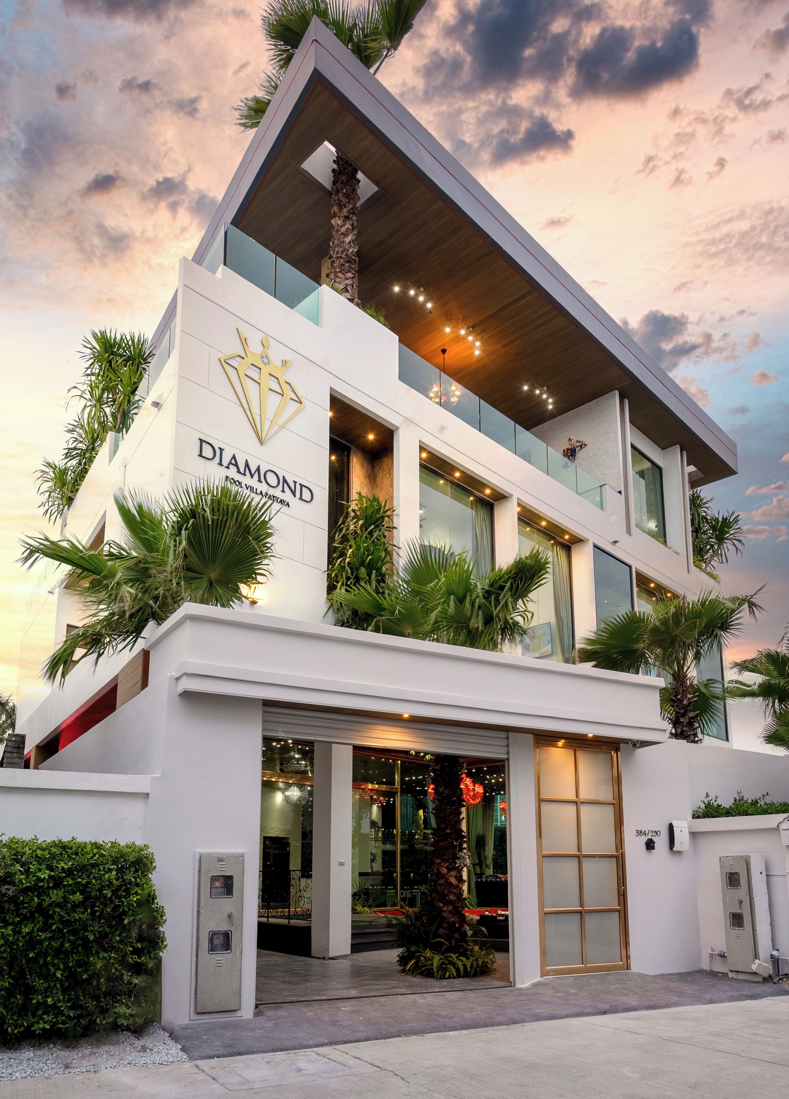 A modern building with a prominent logo and name, large windows, and a balcony with plants.