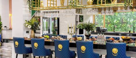 Eine Bar mit blauen Sitzmöglichkeiten, einer goldenen Theke und hängenden Weingläsern.