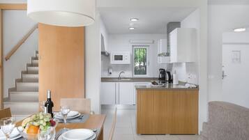 A modern kitchen with white cabinets, a wooden island, and a dining area with a table set for two.