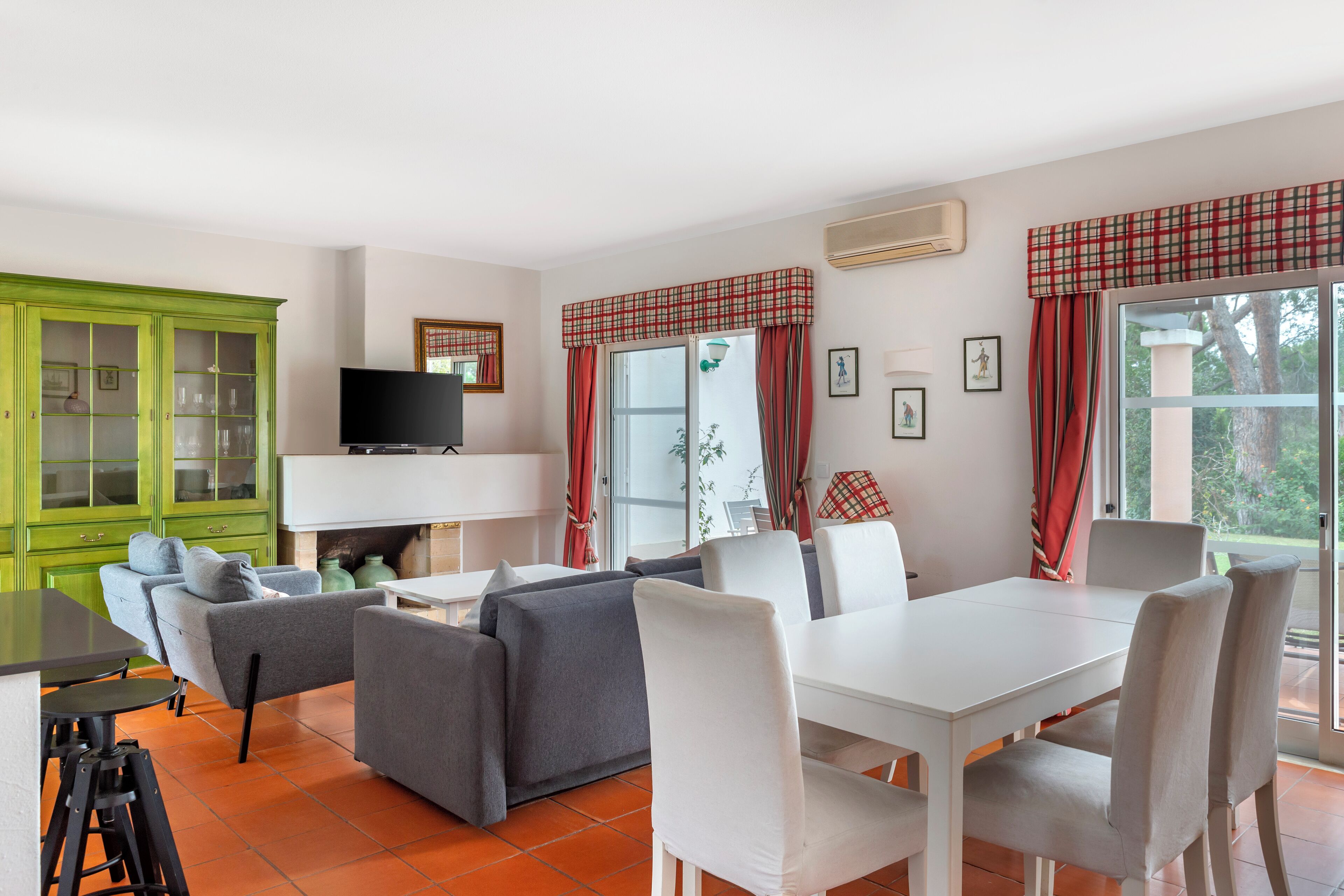 A living room with a sofa, chairs, a dining table, and a TV.