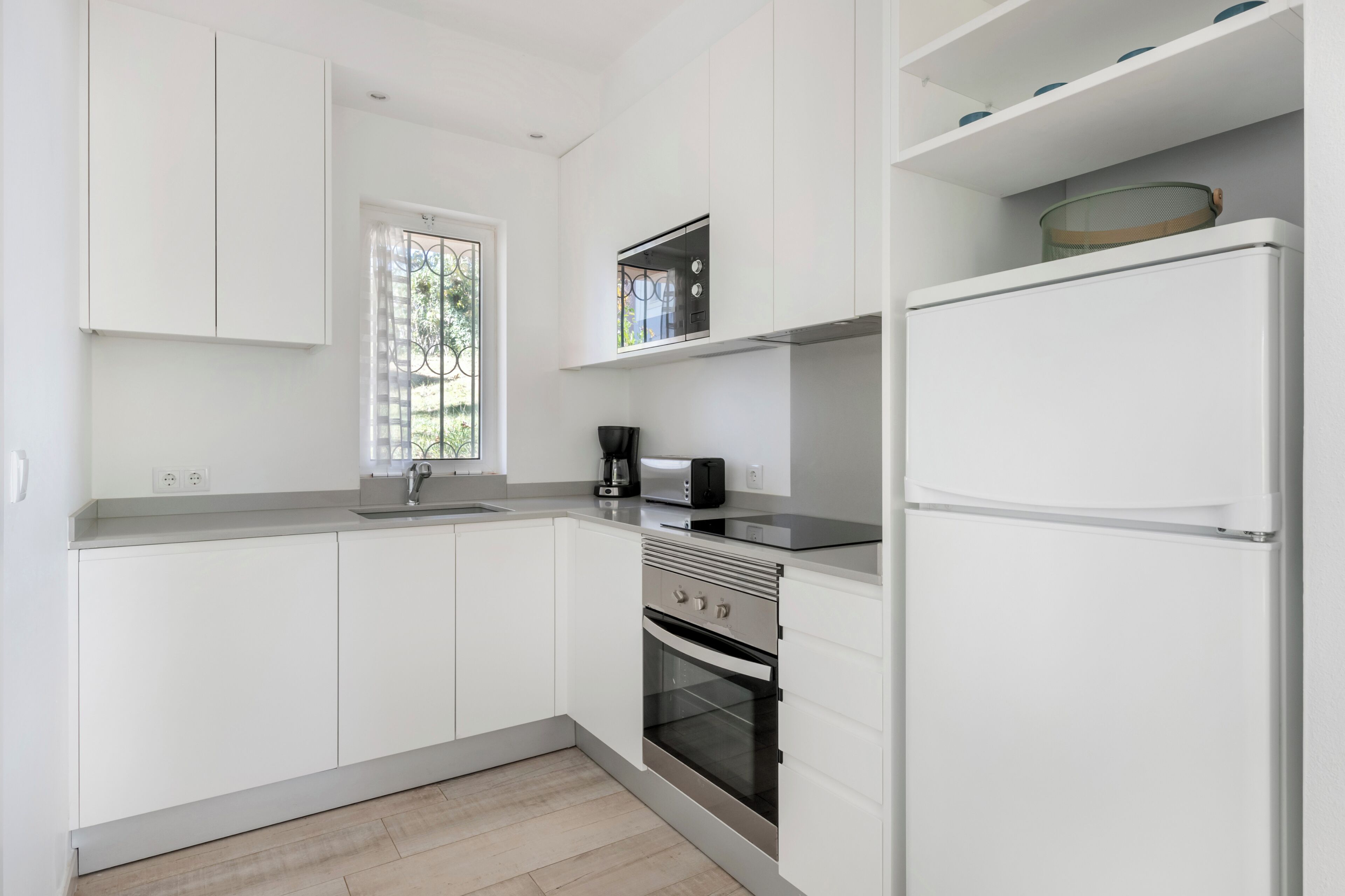 A modern kitchen with white cabinets, a built-in oven, and a refrigerator.