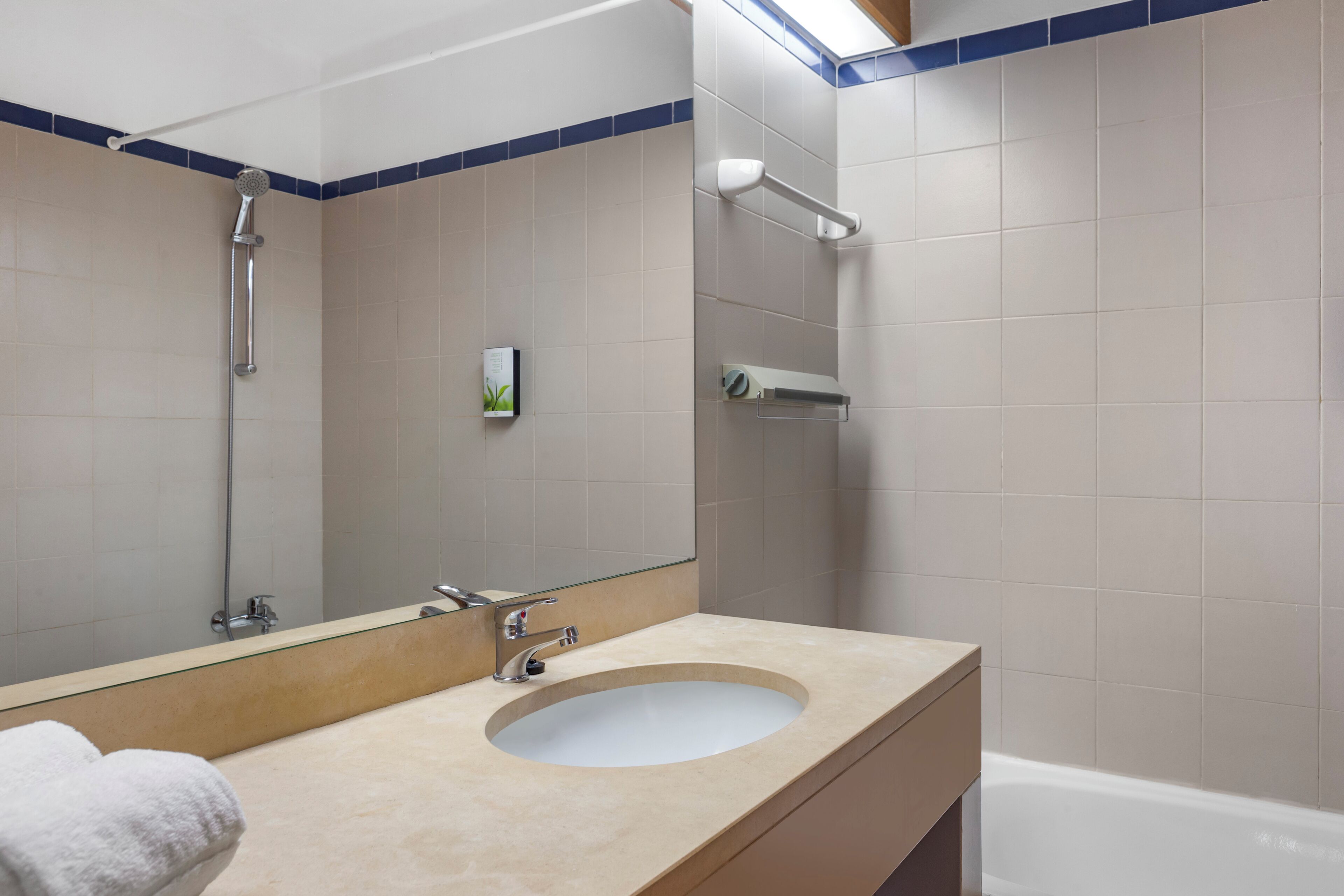 Een badkamer met een wastafel, spiegel en douche.