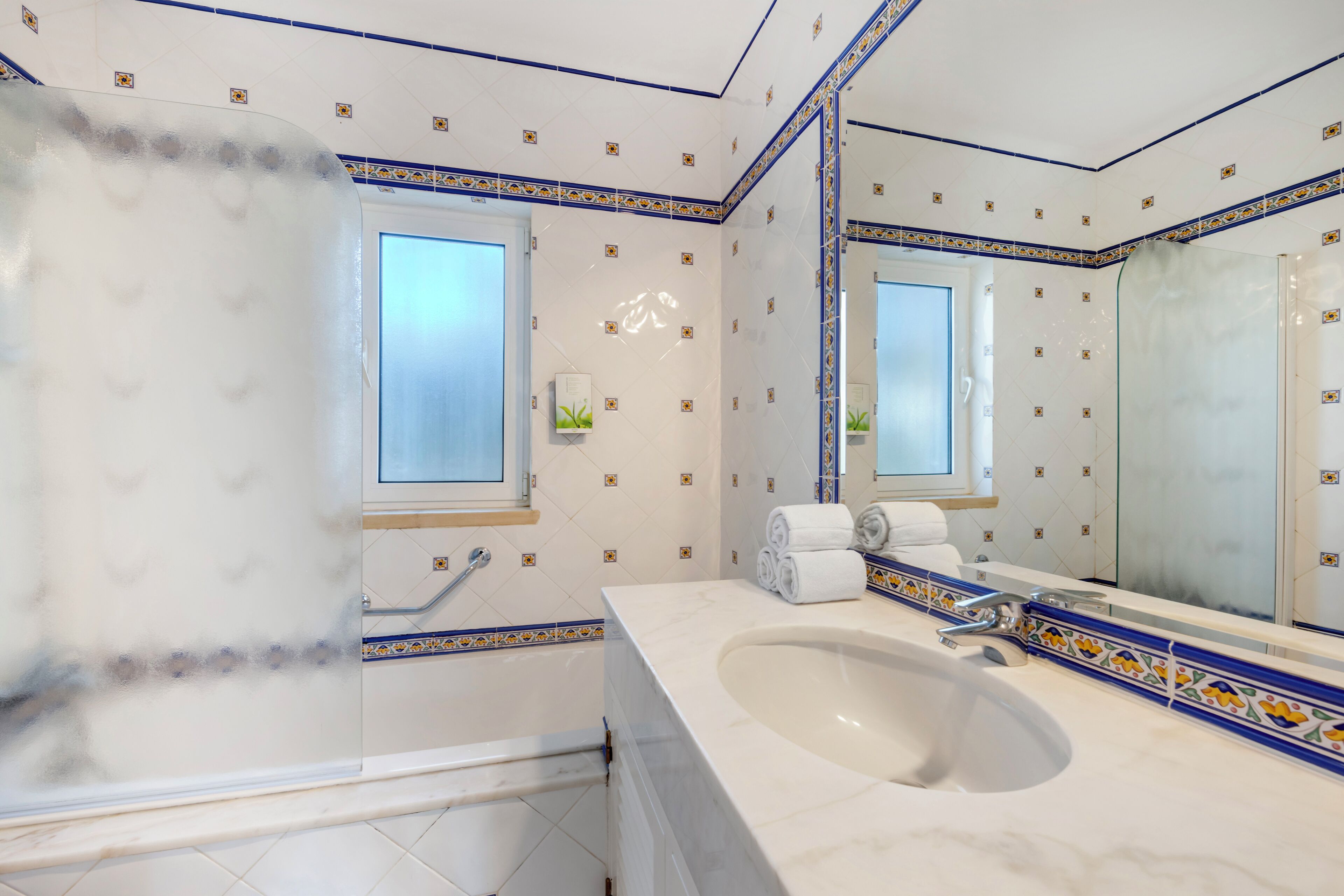A bathroom with a large mirror, a bathtub, and a sink.