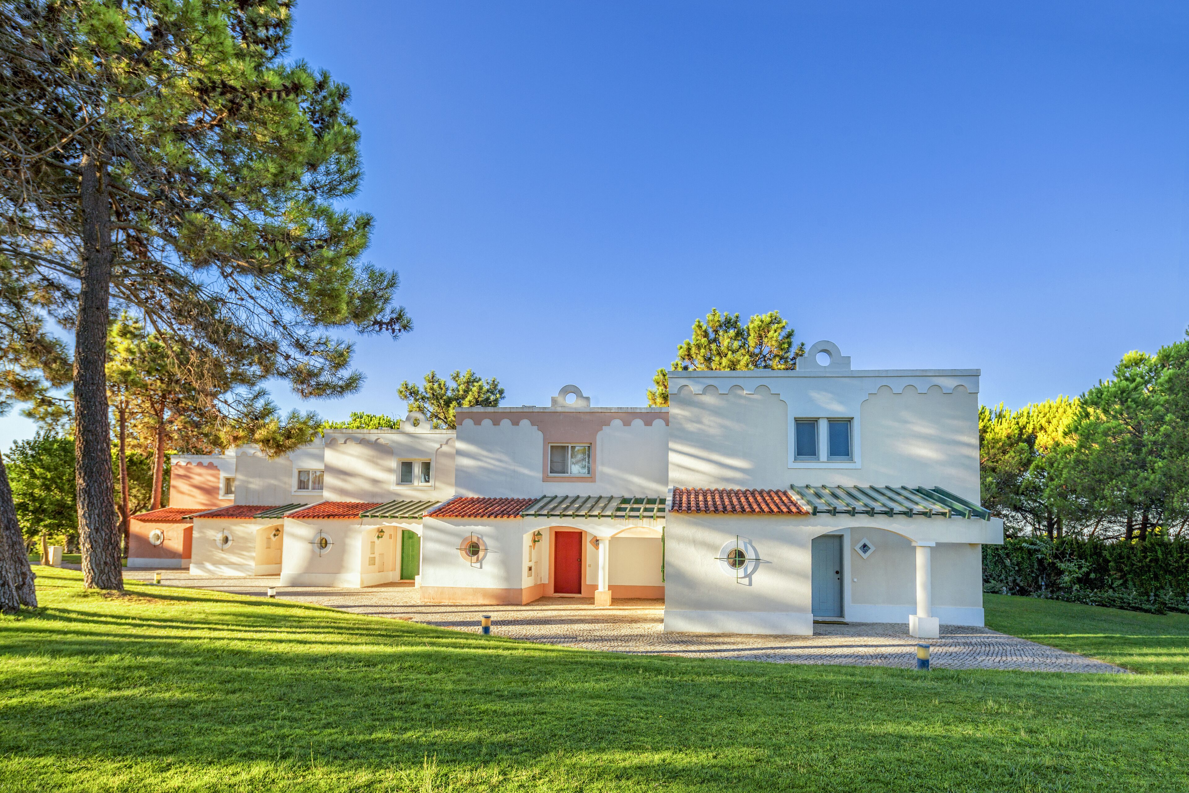 A modern villa with a white exterior, multiple rooms, and a red-tiled roof.