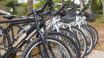 A row of bicycles parked outdoors, with baskets attached to the handlebars.