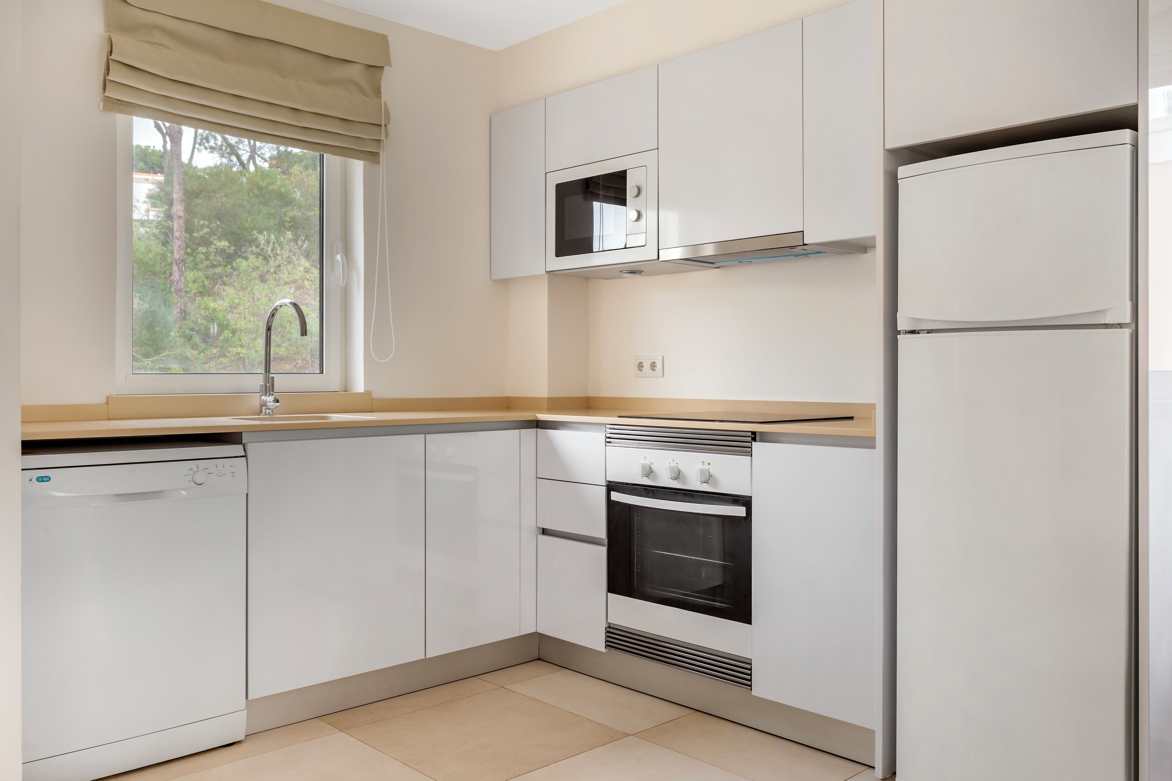 A modern kitchen with white cabinets, a built-in oven, a microwave, and a dishwasher.