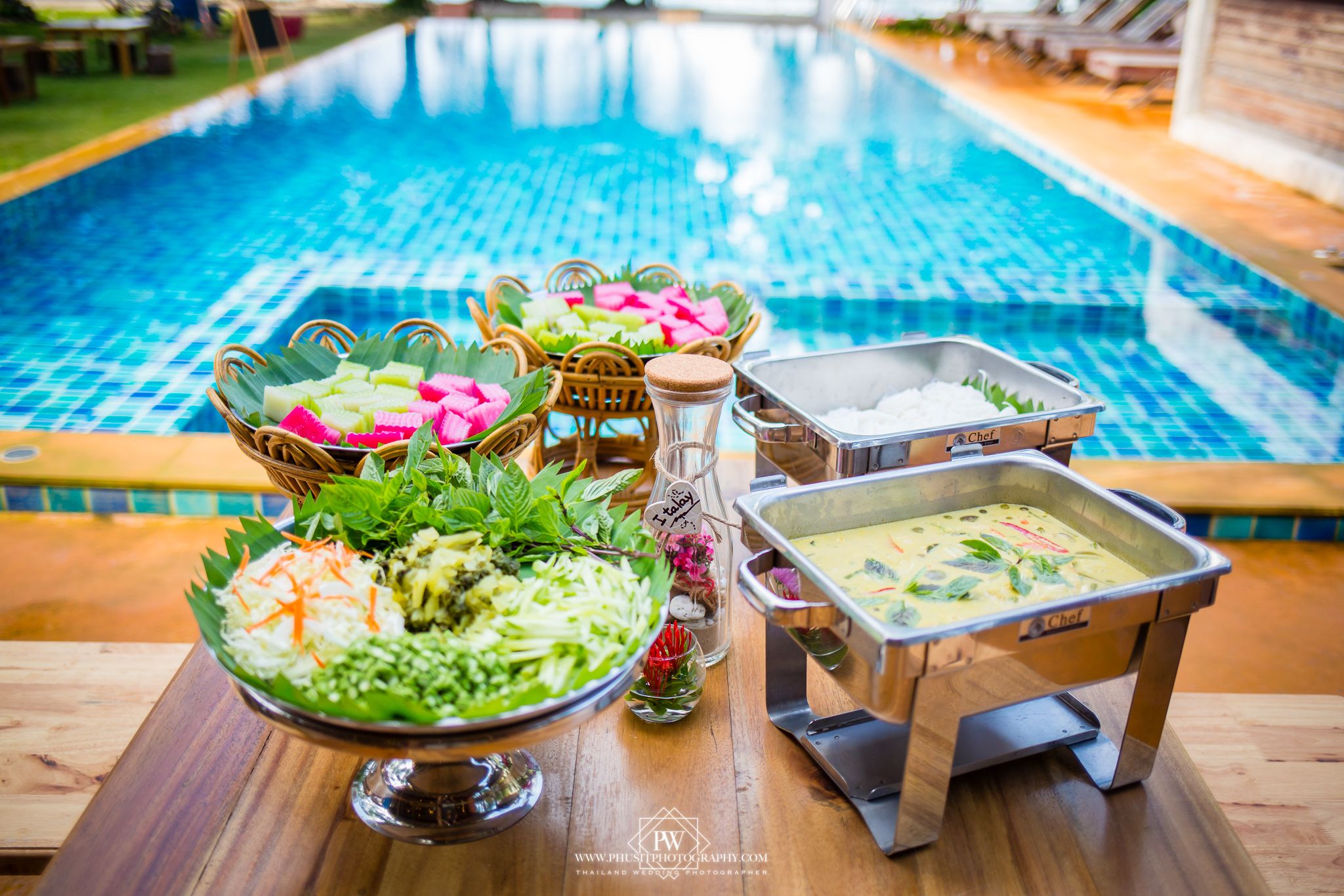 Un buffet au bord de la piscine proposant divers plats et un coin où l’on peut préparer des plats à la chinoise.