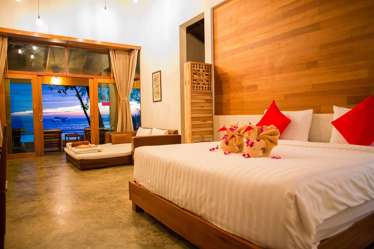 Un dormitorio con una cama grande, cabecera de madera y vista al mar a través de un ventanal.