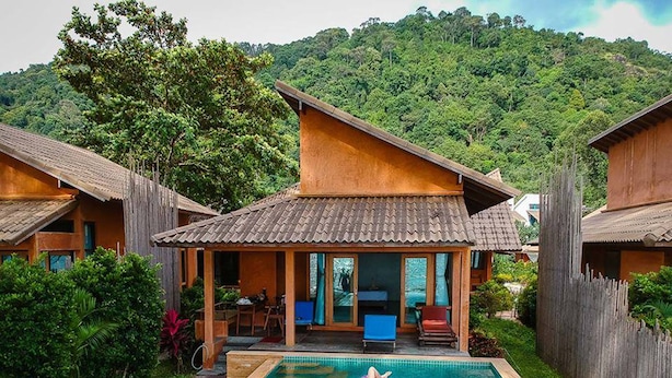 Una cabaña con piscina, rodeada de exuberante vegetación y un paisaje montañoso.