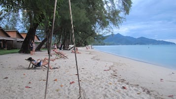 Una playa cerca, sillas reclinables de playa, sombrillas