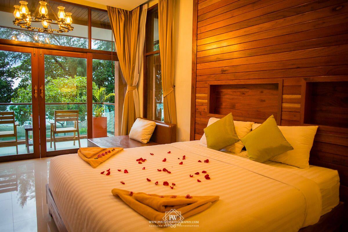 Habitación de hotel con una cama grande, cabecero de madera y vista a zonas verdes.