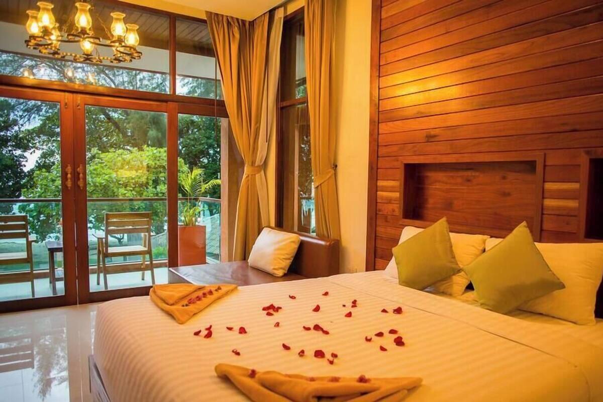 Un dormitorio con una cama grande, cabecera de madera y vistas a zonas verdes.