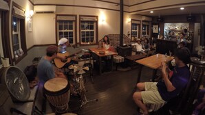 Un bar acogedor con mobiliario de madera, chimenea y un grupo de personas conversando.