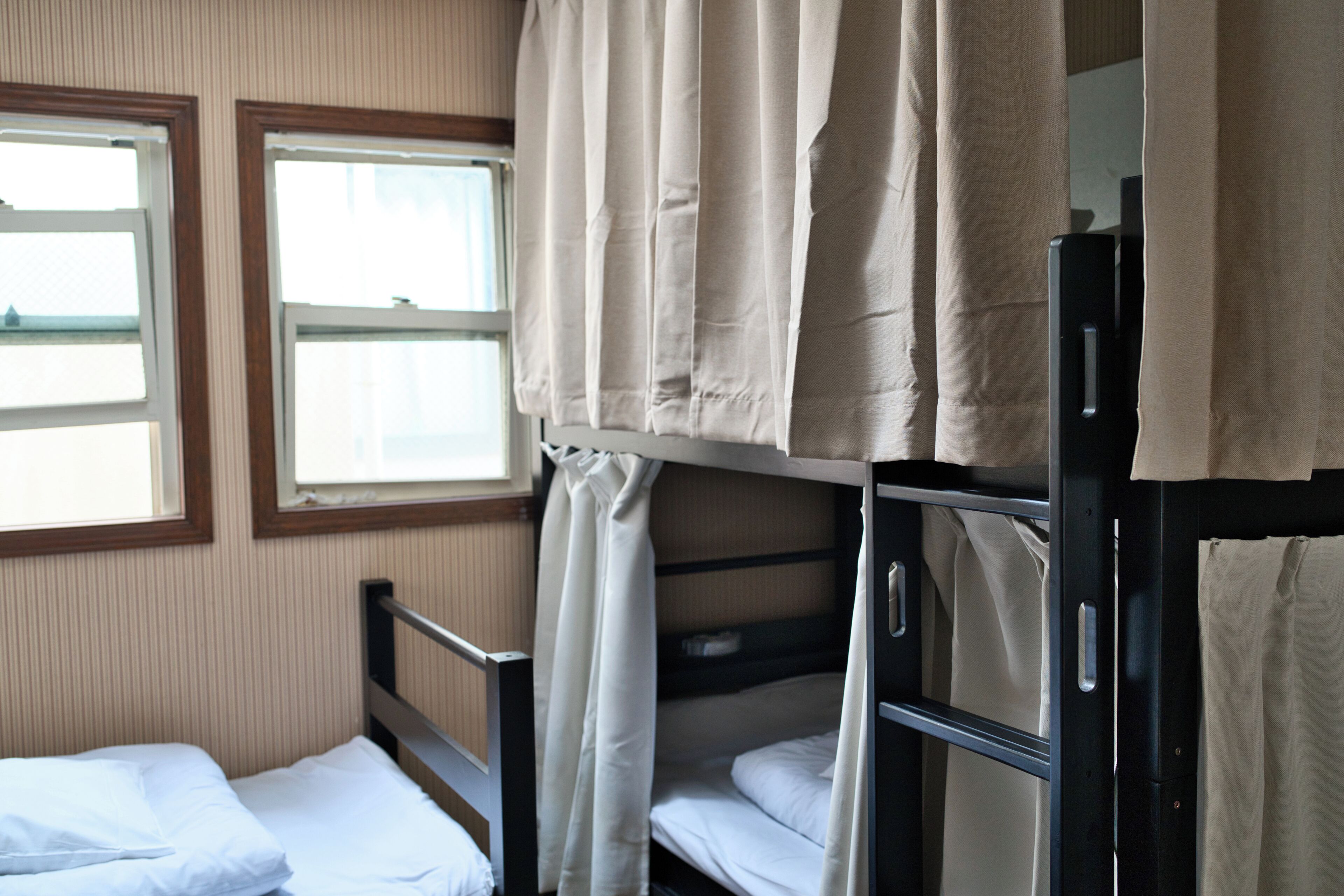 Habitación con literas, dos ventanas y cortinas, y una estructura metálica.