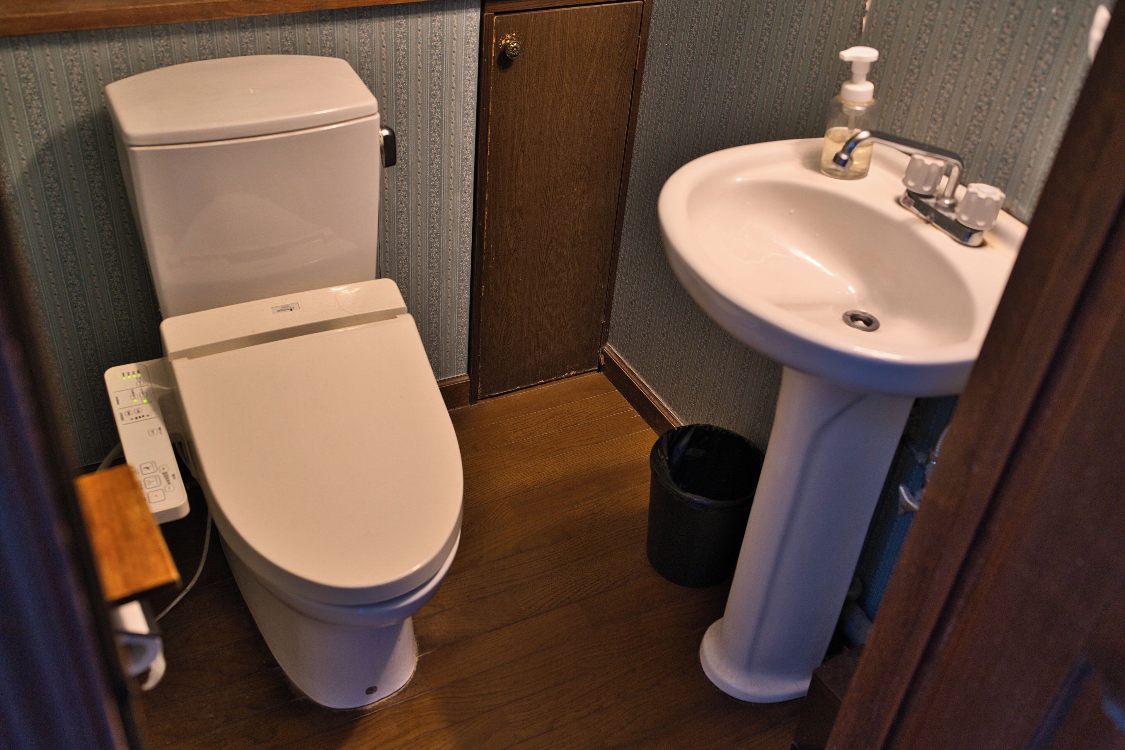 A small bathroom with a toilet, sink, and a trash can.