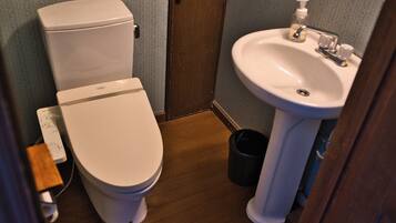 A small bathroom with a toilet, sink, and a trash can.