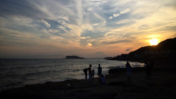 Escena de playa con gente al atardecer.
